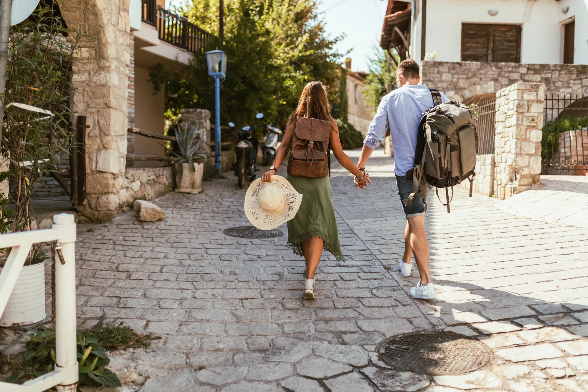 Pareja caminando por una calle empedrada y soleada en un pueblo mediterráneo español